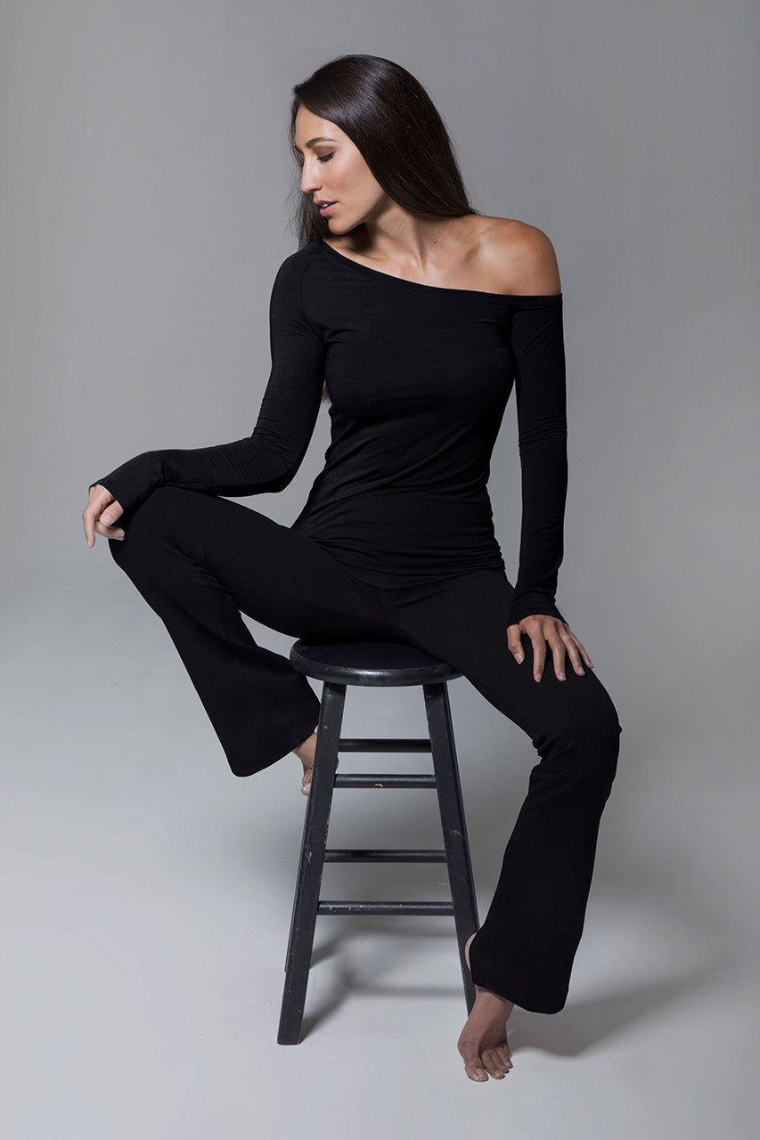 Front view of ULTRA HIGH WAIST GODDESS BOOTCUT: BLACK model sitting on a chair with off the shoulder top 